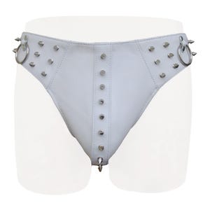 May include: White leather underwear with silver-colored metal studs and spikes. The underwear has a low-rise design with a series of studs down the center and around the edges. Two silver rings are attached to the sides.