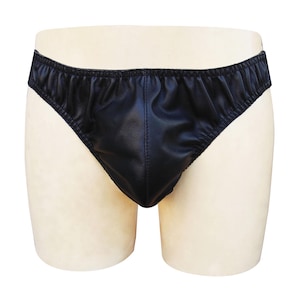 Könnte beinhalten: Schwarze Unterhose aus glattem, glänzendem Material. Der Slip hat einen tiefen Bund und einen konturierten Beutel. Die Kanten sind mit einem dünnen, elastischen Band versehen. Das Kleidungsstück wird auf einer Schaufensterpuppe präsentiert.