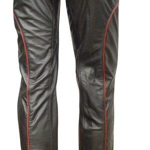 May include: Black leather chaps with red stitching along the sides. The chaps feature a wide belt with two silver buckles. The garment is designed to be worn over other clothing, offering protection and style.