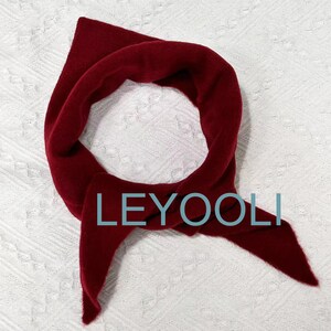 May include: A deep red, fuzzy scarf with the word "LEYOOLI" printed on it.