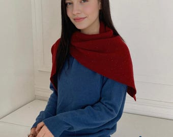 May include: A woman wearing a red scarf over a blue sweater and tan pants. She is holding a brown handbag. The word "yooli" is printed in the lower right corner.