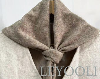 May include: A beige and brown knitted scarf with a knotted design. The scarf is tied around the neck of a garment. The word "LEYOOLI" is printed on the garment.