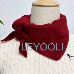 May include: A red fleece neck warmer tied in a knot around a white sweater. The text "LEYOOLI" is visible on the sweater.
