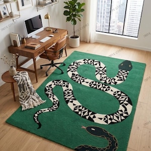 May include: A green rug with a large snake design in white and black. The rug is rectangular and placed on a wooden floor. The snake design is a prominent feature. The rug is a decorative item for the home, suitable for a living room.