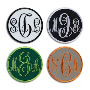 May include: Four round embroidered patches with custom monograms. The patches feature a white, black, green, and gray background with contrasting thread colors. Each patch has a different monogram design, perfect for personalizing clothing or accessories.