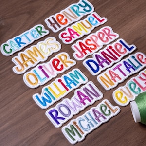 May include: A collection of embroidered name patches featuring the names Carter, Henry, James, Samuel, Oliver, Jasper, William, Daniel, Rowan, Natalie, and Michael, each stitched in colorful thread with a white border on a fabric backing.