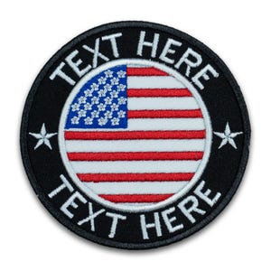 May include: A round, embroidered patch featuring the American flag design. The flag is in a circle, with a black border and white text that reads "TEXT HERE". Two white stars are on the black border.