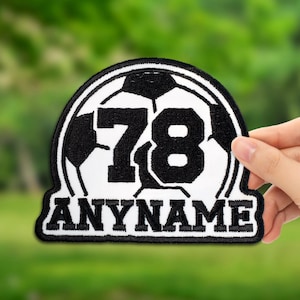 May include: A black and white soccer-themed patch with the number 78 and the word "ANYNAME" in a bold font. The patch features a soccer ball design and is likely for sports apparel or accessories.