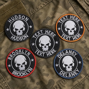 May include: Five circular embroidered patches featuring a white skull graphic in the center. Each patch has text along the border, including HUDSON, BROOKLYN, DELANEY, and TEXT HERE, with colored borders in orange, red, and blue, and white stars.