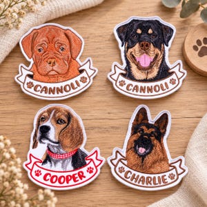 May include: Four embroidered dog patches featuring portraits of a Dogue de Bordeaux, a Rottweiler, a Beagle, and a German Shepherd. Each patch includes a white banner with a name: Cannoli, Cannoli, Cooper, or Charlie, accented with paw prints.