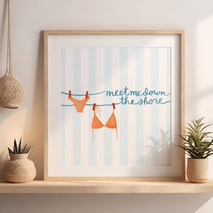 May include: Framed art print featuring an orange bikini top and bottom hanging on a clothesline with red clothespins. The background has blue and white vertical stripes, and the text reads "meet me down the shore."