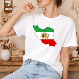 Op de afbeelding: Wit T-shirt met een kaart van Iran in groen, wit en rood, met een gouden leeuwenembleem. Het shirt heeft de tekst "NEXT DAY SHIPPING" in een bruine doos.
