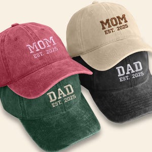 May include: Three vintage-style baseball caps in different colours. The caps are embroidered with the words "MOM EST. 2025" and "DAD EST. 2025".