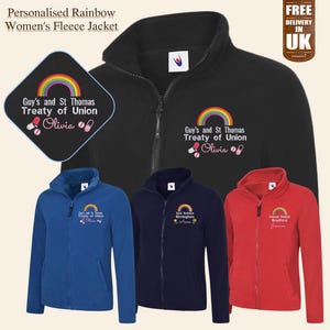 Könnte beinhalten: Eine schwarze Fleecejacke mit einem Regenbogen und dem Text "Guy's and St Thomas Treaty of Union Olivia" auf der Vorderseite. Die Jacke ist in vier verschiedenen Farben dargestellt: Schwarz, Blau, Marineblau und Rot.