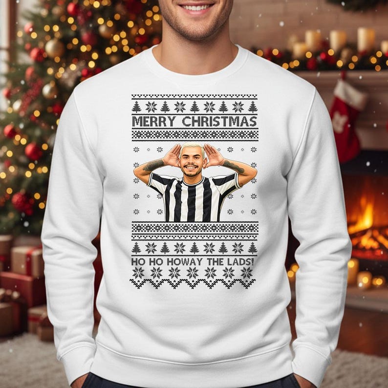 May include: White Christmas sweater with a festive design. The sweater features a graphic of a person with their hands up, and the text "MERRY CHRISTMAS" and "HO HO HOWAY THE LADS!" are displayed across the front. The sweater has a crew neck and long sleeves.