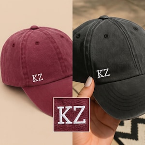 Peut inclure: Deux casquettes de baseball, une bordeaux et une noire, chacune brodée des lettres "KZ" en blanc. Les casquettes ont un design classique à six panneaux, une visière incurvée et une sangle réglable.