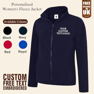 Könnte beinhalten: Eine marineblaue Fleecejacke mit Reißverschluss und einem weißen gestickten Text mit der Aufschrift "YOUR CUSTOM TEXT/LOGO". Die Jacke ist in Schwarz, Marine, Rot und Royalblau erhältlich.