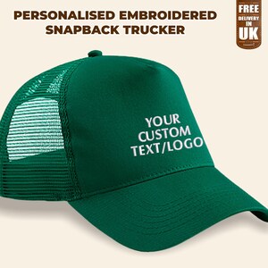 May include: Green trucker hat with a mesh back panel. The hat has white embroidery that says "YOUR CUSTOM TEXT/LOGO".