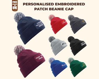 May include: A collection of personalized embroidered patch beanie caps in various colors, including navy, red, gray, black, burgundy, blue, and green. Each cap features a pom-pom and a patch for custom text or logos. The text "YOUR TEXT/LOGO HERE" is visible on some patches.
