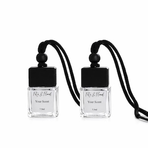 May include: Two clear glass bottles with black caps and black cords. Each bottle has a white label with the text "Fitz & Flood", "Your Scent", and "7.5ml". The bottles are hanging against a white background.