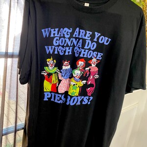May include: Black t-shirt with the text "WHAT ARE YOU GONNA DO WITH THOSE PIE BOYS?" in blue lettering. The shirt features a graphic of several colorful clowns.