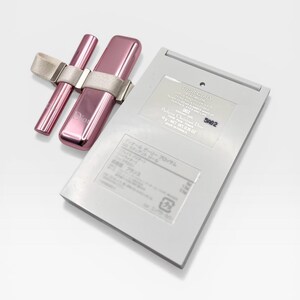 May include: A pink Dior makeup set featuring a lipstick, a lip gloss, and a compact. The lipstick and lip gloss are held together with a beige ribbon. The compact is rectangular and has text on it.