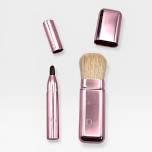 May include: A set of four rose-gold makeup brushes, including a retractable brush with a soft, light-colored bristle head, a small brush with a dark bristle head, and two caps. The brand name "Dior" is visible on the brush.
