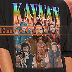 Peut inclure: T-shirt unisexe noir avec un imprimé graphique d'un groupe de personnes avec le texte "KAYVAN" au-dessus. Le modèle porte un t-shirt taille 2XL. Le texte "TSHIRT Unisex" est en haut de l'image.