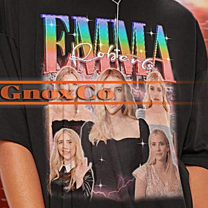 May include: Black oversized t-shirt with a graphic print of a woman's face and the text "Emma Roberts" in rainbow colors. The text "GnoxCo" is also printed on the shirt.