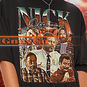 May include: Black t-shirt featuring a graphic print of a group of people with the text "Nick Offerman" above them. The t-shirt is oversized and has a relaxed fit.