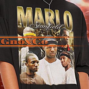 May include: Black t-shirt with a graphic print of Mario Stanfield from the movie "Gnoxx Co."