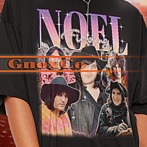 Puede incluir: Camiseta unisex negra con una foto de banda y la palabra "NOEL". La camiseta tiene cuello redondo y mangas cortas. La marca "Tshirt Unisex" está en la parte superior izquierda. La camiseta es de gran tamaño.
