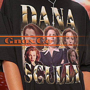 Puede incluir: Camiseta negra con un estampado gráfico de Dana Scully de Expediente X. El gráfico está en un estilo retro con letras doradas y un collage de imágenes de Scully. El texto "Dana Scully" está impreso en letras grandes y en negrita.