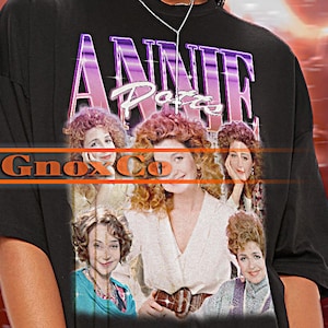 Könnte beinhalten: Schwarzes T-Shirt mit einem Grafikdruck der Besetzung der Fernsehsendung "Annie Potts". Der Text "Gnox Co" ist auf dem Shirt gedruckt.