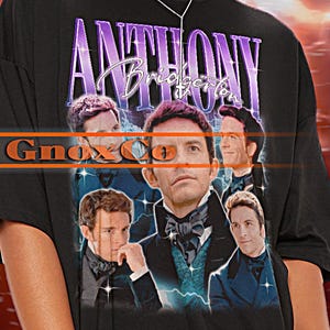 May include: Black oversized t-shirt with a graphic print of a group of men in suits and the text "Anthony Bridgerton" in purple. The text "Gnox Co" is also visible on the shirt.