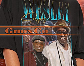 May include: Black unisex t-shirt featuring a graphic of Wesley Snipes. The shirt has the text "WESLEY Snipes" and "GmaxCo" printed on it. The model is wearing a 2XL shirt.