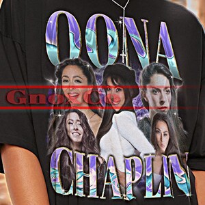 May include: Black unisex t-shirt featuring the text "OONA CHAPLIN" in a colorful, iridescent font. The shirt displays a collage of images of Oona Chaplin. The top left corner reads "TSHIRT Unisex".