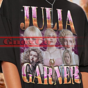 以下が含まれることがあります： スタイリッシュなフォントで「JULIA GARNER」という名前と女優のグラフィックが特徴の黒いユニセックスTシャツ。「TSHIRT Unisex」の文字も含まれています。