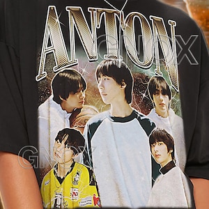May include: Black unisex t-shirt with the name "ANTON" in a vintage style. The shirt features a graphic of five young men. The text "TSHIRT Unisex" is at the top. The model wears a 2XL shirt.