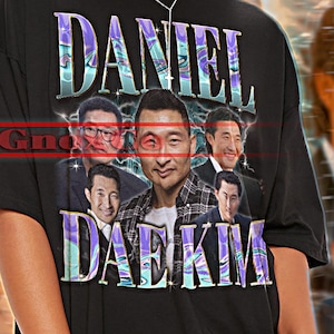 Könnte beinhalten: Schwarzes Unisex-T-Shirt mit dem Text "DANIEL DAE KIM" in einer stilisierten Schriftart. Das Shirt zeigt eine Grafik von Daniel Dae Kim und anderen Bildern. Die Worte "TSHIRT Unisex" stehen oben.
