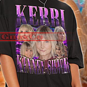 May include: Black unisex t-shirt with a graphic design featuring the name "KERRI" in purple and images of a woman. The shirt also has the text "KENNEY-SILVA". The top left corner of the shirt has the text "TSHIRT Unisex".