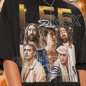 Könnte beinhalten: Schwarzes Unisex-T-Shirt mit einer Collage von Bildern und dem Text "LEE KNOX". Das T-Shirt hat einen Rundhalsausschnitt und kurze Ärmel. Der Text "TSHIRT Unisex" steht oben. Das Model trägt ein Shirt in Größe 2XL.