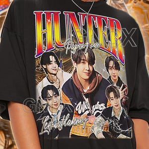 Può includere: T-shirt unisex nera con grafica retrò con la scritta "HUNTER" e immagini di diverse persone. La maglietta include anche il testo "Bapan't com" e "Light Harmony".
