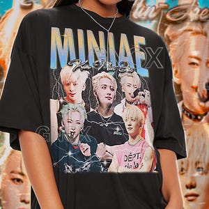 May include: Black unisex t-shirt featuring a graphic of a musical group with the text "MINJAEX" in a stylized font. The shirt also has the text "TSHIRT Unisex". The model wears a 2XL shirt.