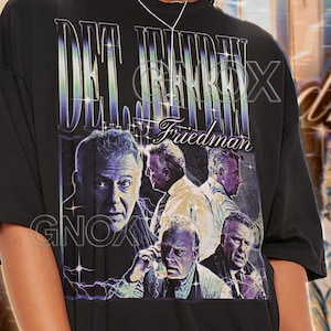 May include: Black unisex t-shirt featuring a graphic design with the text "DET. JEFFREY FRIEDMAN" and multiple images of a man. The shirt also has the text "GNOX" at the bottom. The shirt is a unisex size.