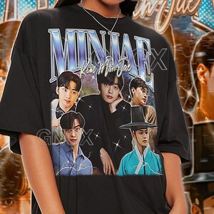 May include: Black unisex t-shirt featuring a graphic of several people with the text "MINJAE" in a stylized font. The shirt also has the text "Kim Minjae" and "GNOX". The shirt is labeled "TSHIRT Unisex".