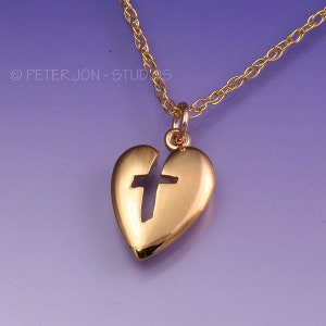 May include: A gold heart-shaped pendant necklace with a cross cut out of the center. The necklace is on a gold chain.