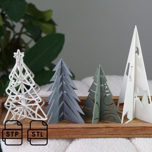 May include: Five 3D printed Christmas trees in different colors and designs. The trees are arranged on a wooden tray. The trees are white, gray, green, and a lighter shade of green. The trees are all different sizes and shapes. The trees are made of a material that looks like paper or plastic. The trees are all decorated with a star on top. The image also includes the text "STP" and "STL".