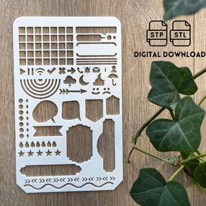May include: A white plastic stencil with various shapes and icons for bullet journaling or planning. Includes grids, speech bubbles, banners, and weather symbols. The text "DIGITAL DOWNLOAD" is visible.