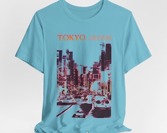 May include: A light blue t-shirt featuring a graphic of a cityscape with cars and buildings in shades of red, orange, and black. The text "TOKYO JAPAN" is printed across the top in orange.